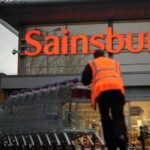 An employee moves shopping trolleys in front of a Sainsbury's store in London. AFP/GETTY