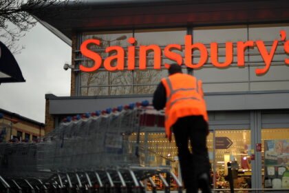 An employee moves shopping trolleys in front of a Sainsbury's store in London. AFP/GETTY