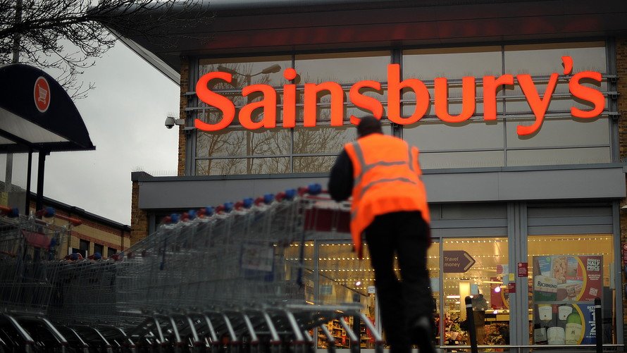 An employee moves shopping trolleys in front of a Sainsbury's store in London. AFP/GETTY